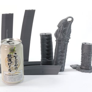 May include: Five 3D printed gray plastic pieces, including a tall, slender piece with a decorative top, a shorter, wider piece with a decorative top, and three rectangular pieces. A can of Japanese beer is in the foreground.