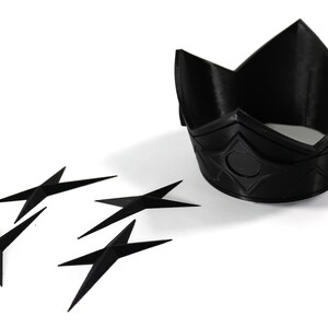 May include: A black plastic crown with a diamond pattern and a black plastic star-shaped object.