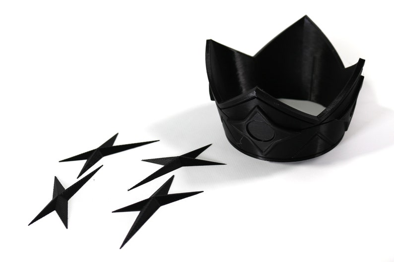 May include: A black plastic crown with a diamond pattern and a black plastic star-shaped object.