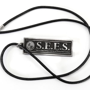May include: A black cord necklace with a silver pendant. The pendant is rectangular and has the text "S.E.E.S. SPECIALIZED EXTRACURRICULAR EXECUTION SQUAD" on it.