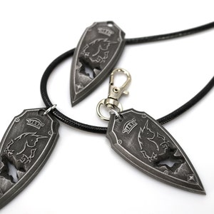 May include: Three silver-toned pendants with a black unicorn design. The pendants are attached to black cords, one of which is a necklace and the other two are keychains.