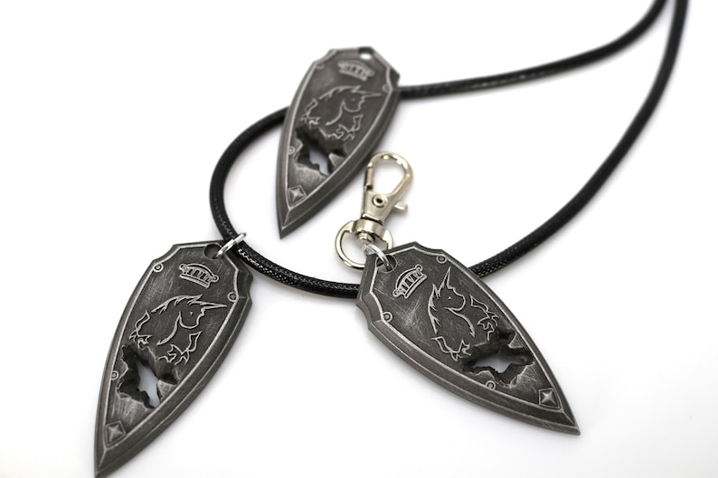 May include: Three silver-toned pendants with a black unicorn design. The pendants are attached to black cords, one of which is a necklace and the other two are keychains.