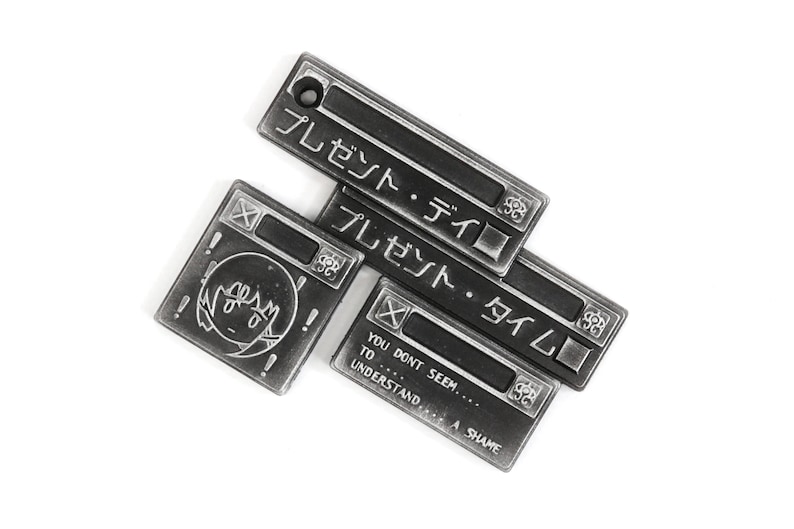 May include: Three silver metal keychains with Japanese text that reads "Present Day" and "Present Time". The third keychain has the text "You don't seem... to understand... A shame".