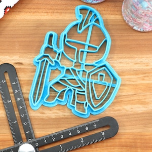 May include: Blue plastic cookie cutter shaped like a knight holding a sword and shield.