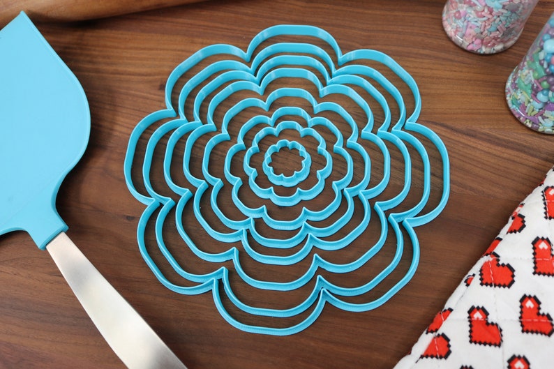 May include: A set of seven blue plastic flower-shaped cookie cutters of varying sizes.
