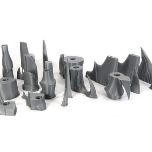Peut inclure: Un ensemble de 17 pi&egrave;ces en plastique gris imprim&eacute;es en 3D, probablement pour une maquette ou un jeu de figurines. Les pi&egrave;ces sont de formes et de tailles vari&eacute;es, notamment des pointes, des lames et d'autres formes g&eacute;om&eacute;triques.