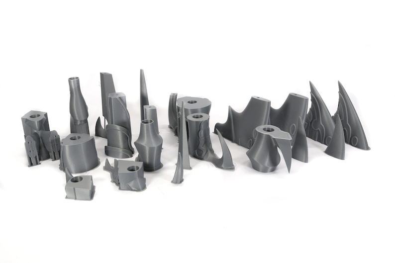 Peut inclure: Un ensemble de 17 pi&egrave;ces en plastique gris imprim&eacute;es en 3D, probablement pour une maquette ou un jeu de figurines. Les pi&egrave;ces sont de formes et de tailles vari&eacute;es, notamment des pointes, des lames et d'autres formes g&eacute;om&eacute;triques.