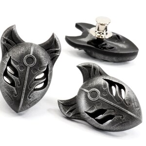 Op de afbeelding: Drie zilverkleurige metalen vossenmasker-spelden. De maskers hebben ingewikkelde details en een textuur. De spelden zijn ontworpen om op kleding of tassen te worden gedragen.