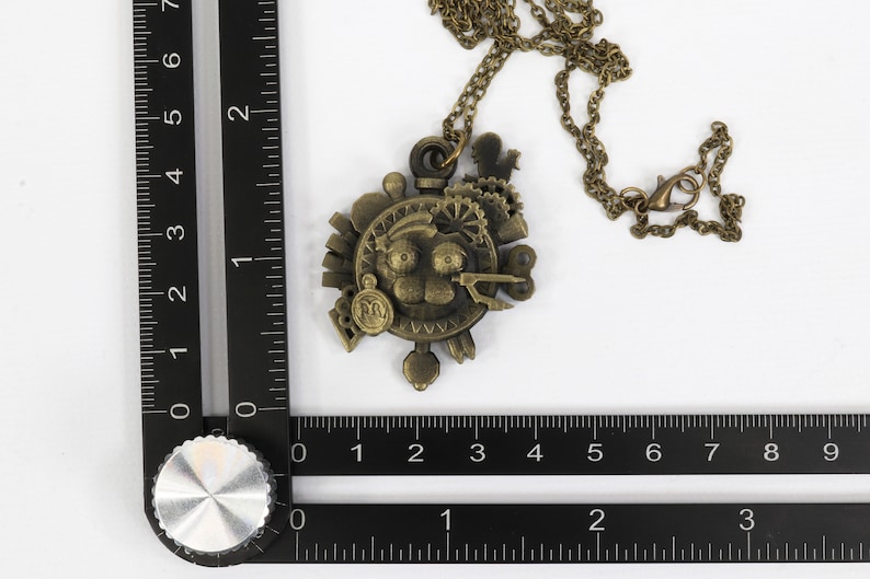 May include: A bronze steampunk-style necklace with a circular pendant featuring gears, cogs, and a face. The pendant is about 2 inches in diameter.
