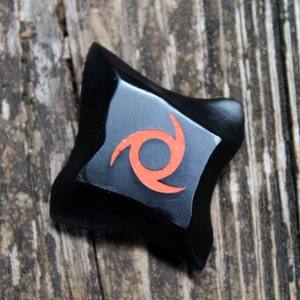 May include: Black star-shaped object with a red swirl design.