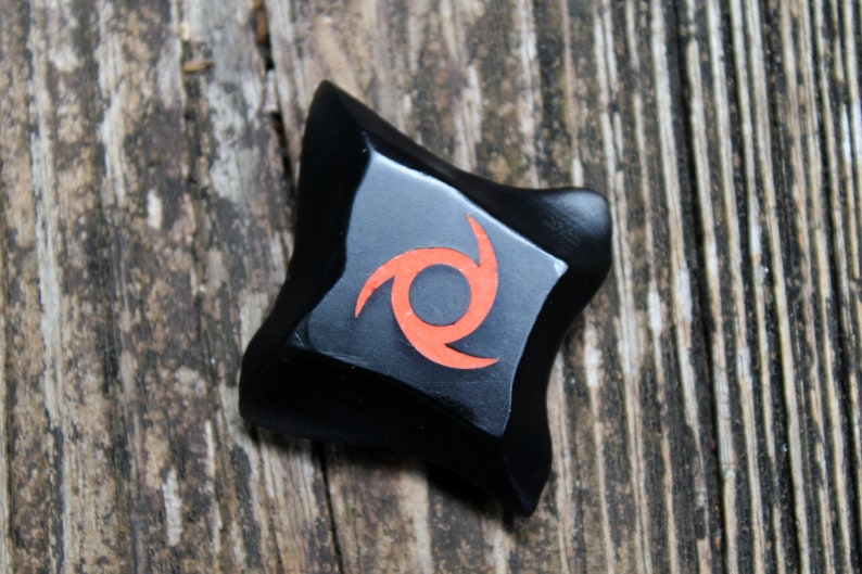 May include: Black star-shaped object with a red swirl design.