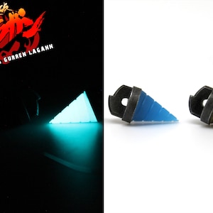 May include: The image features two drill-shaped objects, one glowing turquoise and the other in blue and bronze. The objects are set against a white background, with the text "Tengen Toppa Gurren Lagann" visible in the upper left corner.