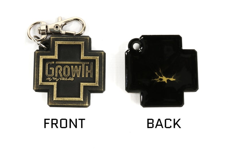 May include: A black leather keychain with a gold cross design. The front of the keychain features the word "GROWTH" in gold lettering. The back of the keychain has a gold splatter design.
