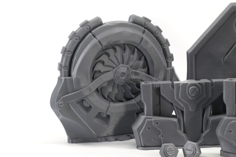 May include: A set of 3D printed gray plastic parts for a robot or machine. The parts include a large fan-like wheel, a smaller rectangular piece with a screw, and a flat piece with a raised design.