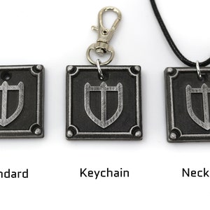 May include: Three silver-coloured metal pendants featuring a shield design. The pendants are displayed in three different styles: standard, keychain, and necklace.