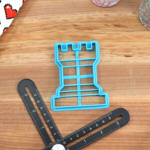 May include: A blue plastic cookie cutter shaped like a chess rook.