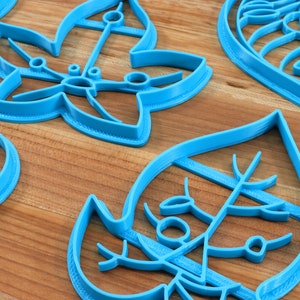 May include: Set of five blue plastic cookie cutters shaped like leaves. The cutters have intricate designs and are perfect for making cookies or fondant decorations.