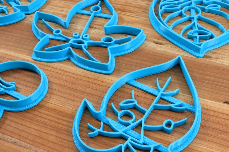 May include: Set of five blue plastic cookie cutters shaped like leaves. The cutters have intricate designs and are perfect for making cookies or fondant decorations.