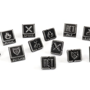 May include: A set of 10 black and silver metal dice with various symbols and text, including "Fight", "Magic", "Spare", "Act", "Item", "Defend", "Alt", and "Magic".