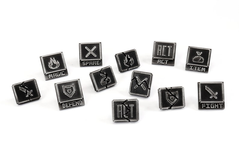 May include: A set of 10 black and silver metal dice with various symbols and text, including "Fight", "Magic", "Spare", "Act", "Item", "Defend", "Alt", and "Magic".