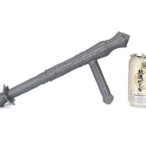 May include: A gray 3D printed weapon with a handle and a spiked end. The weapon is next to a can of Japanese beer with the text "二番搾り 生ビール" on the label.
