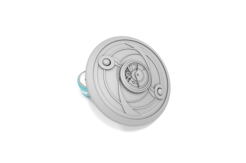 May include: A gray, circular decorative object with an intricate design featuring concentric circles and a clock-like mechanism. The object has a light blue accent on the side. The design is reminiscent of a shield or a steampunk aesthetic.