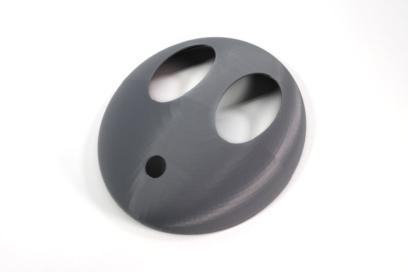 May include: A gray 3D printed mask with two large oval cutouts and a smaller round cutout in the center.