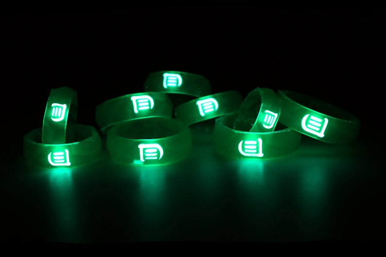 May include: A group of green glow-in-the-dark silicone rings with a white logo on each ring.