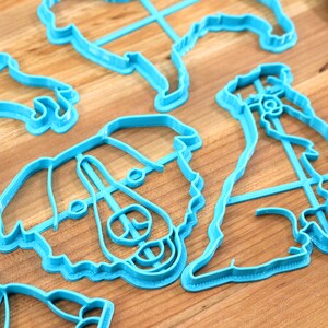May include: A set of blue plastic cookie cutters shaped like dogs. The cutters are on a wooden surface.
