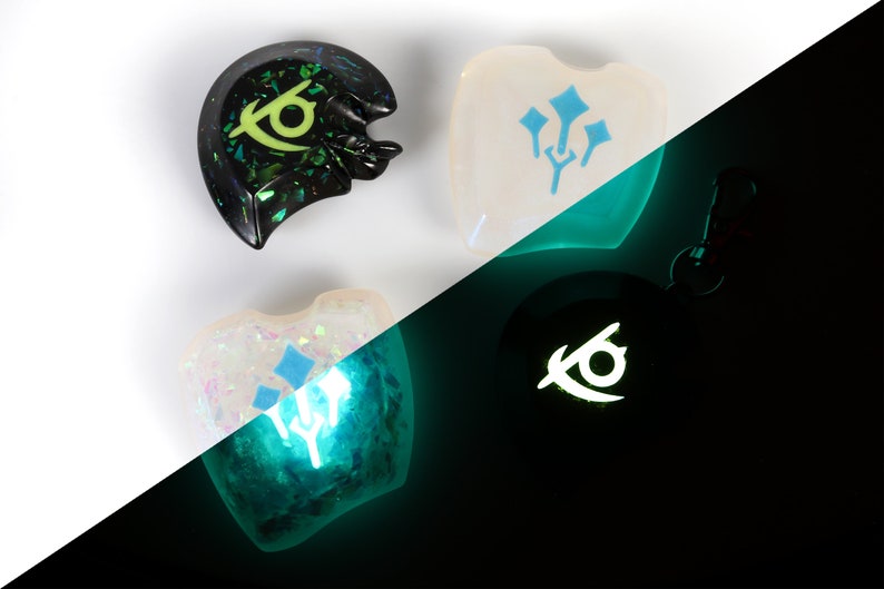 May include: Four resin charms, two with a blue and white design and two with a black and green design. The charms glow in the dark, with the blue and white charms glowing green and the black and green charms glowing white.