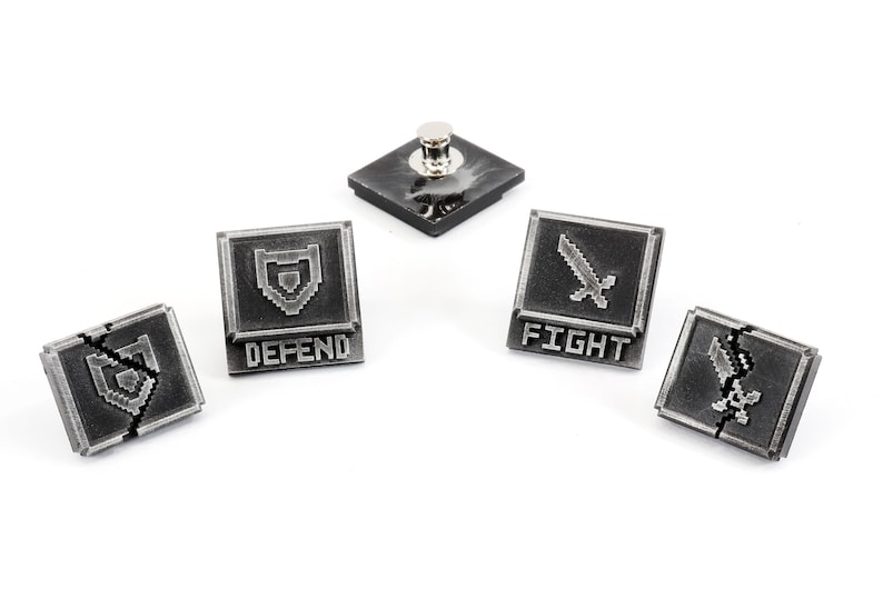 May include: Five silver-toned metal pins with pixelated graphics. The pins feature a sword, a shield, and the words "FIGHT" and "DEFEND".