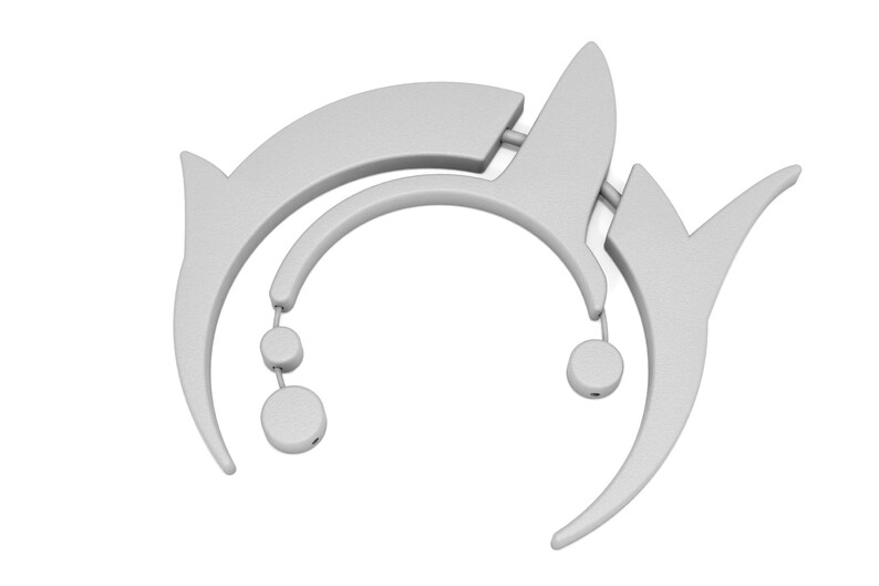 May include: A light gray, abstract, decorative object with curved lines and circular accents. The design features a series of interconnected shapes, including arcs and pointed elements, with small, dangling circular details. The overall aesthetic is modern and minimalist.