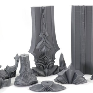 May include: A set of eight gray 3D printed pieces that can be assembled into a sword. The pieces are detailed with intricate designs and have a smooth, matte finish.