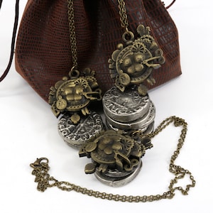 May include: A set of three silver and bronze necklaces with intricate designs. The necklaces are displayed on a brown leather pouch with a drawstring closure.