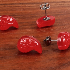May include: Four red earrings with a floral design. The earrings are made of a smooth, shiny material and have a silver post.