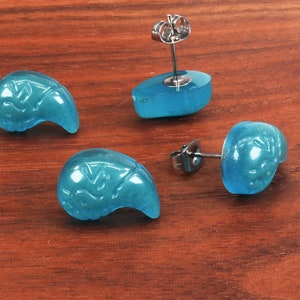 May include: Four turquoise blue earrings with a carved design. The earrings are made of a smooth, polished material and have a silver post.