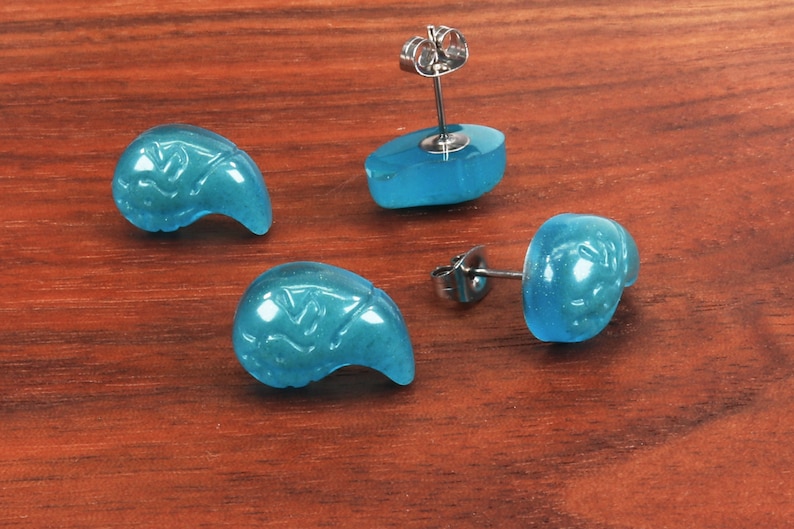 May include: Four turquoise blue earrings with a carved design. The earrings are made of a smooth, polished material and have a silver post.