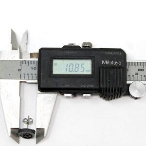 May include: A close-up of a digital caliper measuring a small black earring. The caliper reads 10.85 mm.