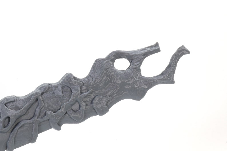 May include: A gray 3D printed sword with a detailed, organic design. The blade is curved and has a textured surface.