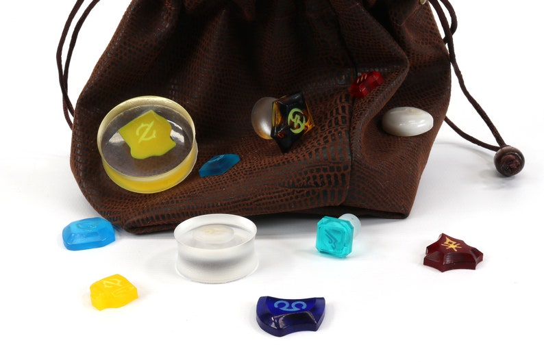 May include: A brown leather dice bag with a drawstring closure, spilling out a variety of colorful dice with different symbols. The dice are made of clear glass with various colors and symbols.