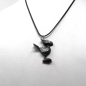 May include: A black necklace with a geometric bird pendant. The bird is made of a dark gray material and has a detailed design.
