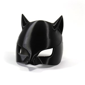 May include: A black plastic cat mask with pointy ears and eye holes.