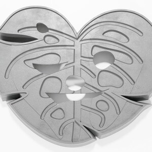 May include: A gray, heart-shaped, decorative wall hanging with a cutout design resembling a monstera leaf.
