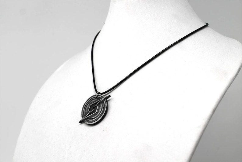 May include: A black necklace with a silver pendant featuring a stylized lightning bolt design.