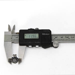 Op de afbeelding: Een zilveren digitale schuifmaat die 3,04 cm meet. De schuifmaat heeft een zwart display en een zilveren liniaal met zwarte markeringen.