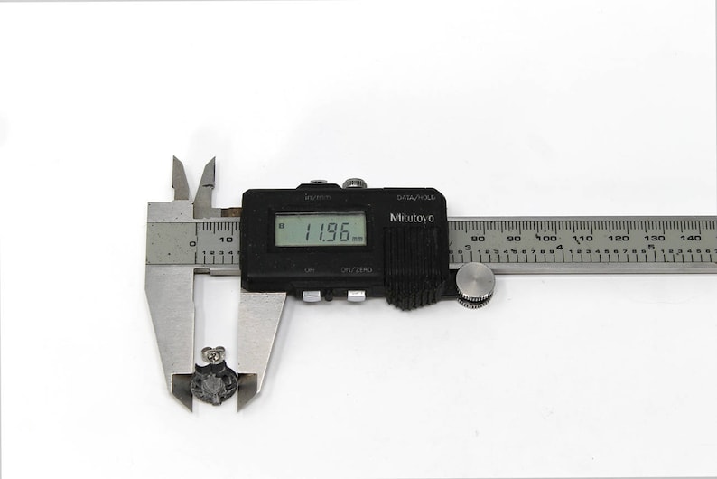 Op de afbeelding: Een zilveren digitale schuifmaat die 3,04 cm meet. De schuifmaat heeft een zwart display en een zilveren liniaal met zwarte markeringen.
