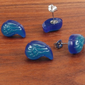 May include: A pair of blue teardrop-shaped earrings with a carved design. The earrings have silver posts and backs.