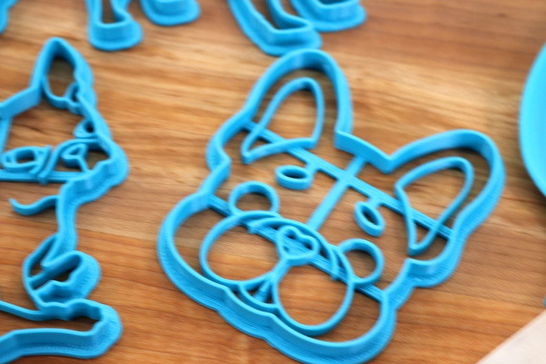Puede incluir: Un cortador de galletas de pl&aacute;stico azul con forma de cabeza de perro. El cortador tiene un dise&ntilde;o detallado de la cara del perro, incluyendo la nariz, los ojos y las orejas.