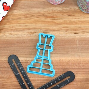 May include: A blue plastic cookie cutter shaped like a chess rook.