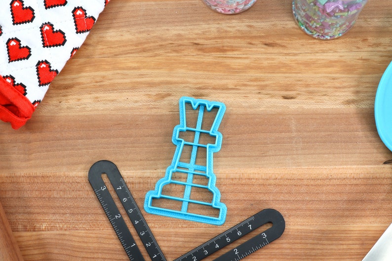 May include: A blue plastic cookie cutter shaped like a chess rook.
